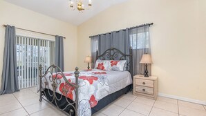Una camera da letto con un letto, comodini, un lampadario e vista attraverso una finestra con tende.
