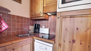 Een compacte keuken met houten kastjes, een roestvrijstalen spoelbak, een koffiezetapparaat en een Siemens vaatwasser.