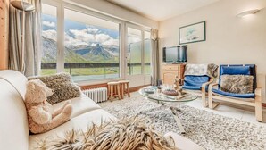 Un salon confortable avec un canapé, un fauteuil, une table basse et un téléviseur.