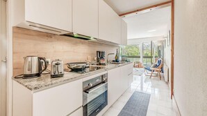 Une cuisine moderne dotée d’un grand îlot central, d’un four encastré et donnant sur un balcon.