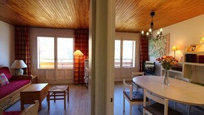 A cozy living room with a wooden ceiling, a sofa, a dining table, and a TV. - 100m from ski slopes, 4th floor, view lake/mountain, balcony, tv, ski locker, 62m², Tignes (Tignes)