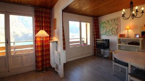 A cozy room with wooden floors, a dining table, a TV, and a radiator. - 100m from ski slopes, 4th floor, view lake/mountain, balcony, tv, ski locker, 62m², Tignes (Tignes)