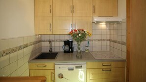 A kitchen with wooden cabinets, a coffee maker, a vase with flowers, and a dishwasher. - 100m from ski slopes, 4th floor, view lake/mountain, balcony, tv, ski locker, 62m², Tignes (Tignes)