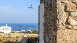 Ein Duscbereich im Freien mit Steinwänden und Blick aufs Meer.
