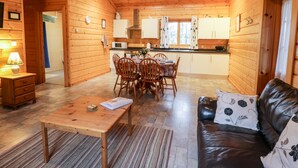 A cozy cabin interior with a dining area, a leather sofa, and a kitchen. - Chloe's Lodge (Pickering)