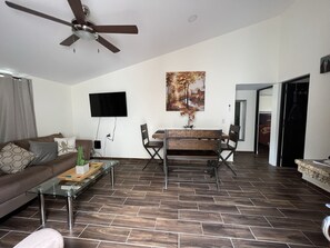 A living room with a sofa, coffee table, TV, and dining area.