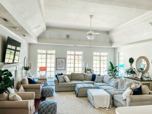 Relax in this inviting living room with a fireplace, comfortable seating, and natural light from large windows.