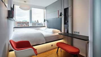 A modern bedroom with a bed, a desk, a chair, and a bench.