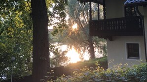 Ein Gebäude mit einem Balkon, der auf einen Garten mit Bäumen und Sonnenuntergang Blick bietet.