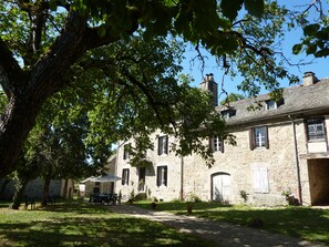 Un bâtiment en pierre doté de nombreuses fenêtres et d’un patio couvert.