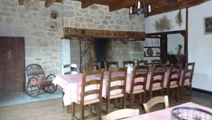 Un comedor rústico con paredes de piedra, vigas de madera y una araña.