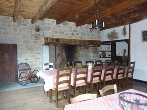 Un coin repas rustique avec des murs en pierre, des poutres en bois et un lustre.