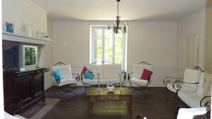 Una sala de estar con mobiliario blanco, una mesa de centro de madera y una araña.