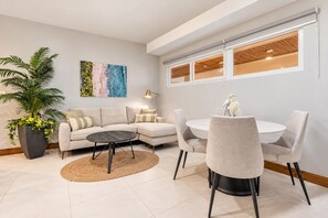 A modern living room with a sofa, a coffee table, and a dining area with chairs and a table.