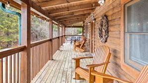 A wooden deck with Adirondack chairs and a table, overlooking a forested area. - SMOKY MTN STAYS OFF LAKE w/POOL & HOT TUB (Sevierville)