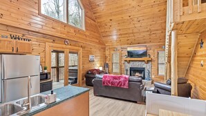 A cabin interior with a kitchen, living area, and fireplace. - SMOKY MTN STAYS OFF LAKE w/POOL & HOT TUB (Sevierville)