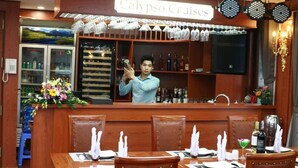 Interior de restaurante com área de bar, mesas bem organizadas e um letreiro com a inscrição 'Calypso Cruises'.