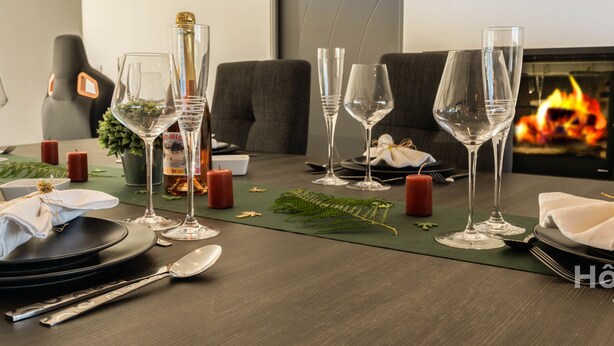 A dining table set with wine glasses, plates, and cutlery, with a fireplace in the background. - La Vedrenne: Smart Barn near Limoges (Bonnac-la-Côte)