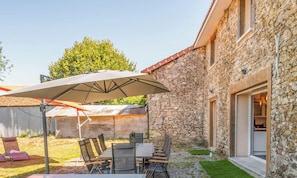 A stone building with a patio area featuring a table, chairs, and umbrellas.