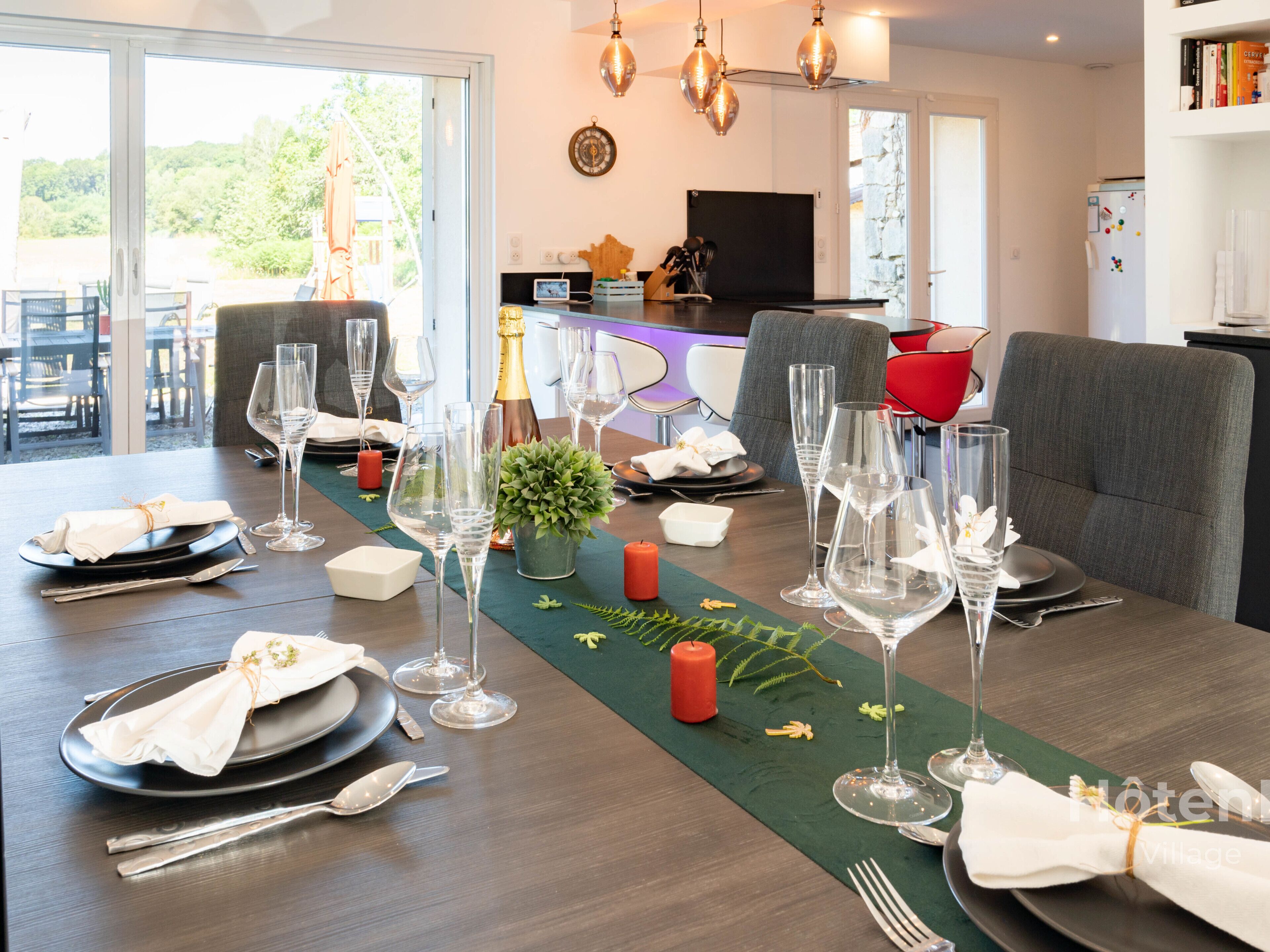 Una mesa de comedor lista para una comida, con copas de vino, platos y cubiertos.