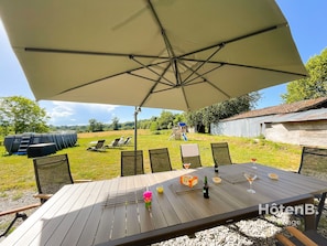 An outdoor seating area with a table, chairs, and a large umbrella.
