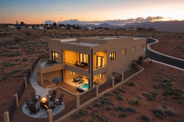 A multi-story building with a pool, outdoor seating, and a desert landscape in the background.