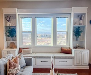 Un salon doté d’une banquette intégrée, de meubles blancs et d’une grande fenêtre offrant une belle vue.