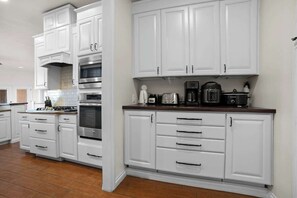 A kitchen with white cabinetry, a built-in oven, and a coffee maker on the countertop.