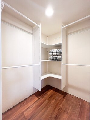 A walk-in closet with white shelving and a wooden floor.