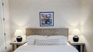 A hotel room with a bed, two bedside tables with lamps, a headboard, and a framed picture on the wall. - The Cliff Dweller - 3400sf, 50-Mile Views, Hot Tub (Page)