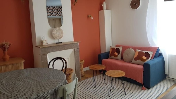 Un salón con sofá, chimenea, espejo redondo y un reloj en la pared.