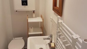 Un baño pequeño con inodoro, lavamanos y espejo.