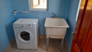 A compact laundry area with a washing machine and a sink. - Awesome Homes - Panoramic Heights (Gros Islet)