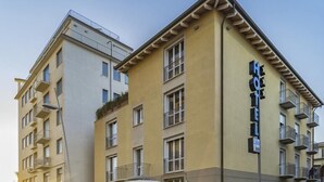 A hotel with a yellow facade, multiple balconies, and outdoor seating. - Hotel Lido Inn (Camaiore)
