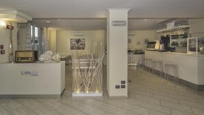 A hotel lobby with a reception desk, bar area, and seating. - Hotel Lido Inn (Camaiore)