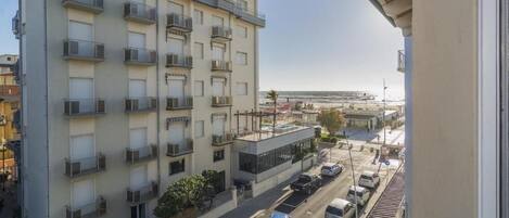 Un edificio de varios pisos con balcones, un estacionamiento y vista al mar.