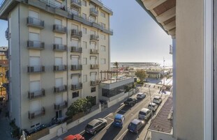 Un edificio de varios pisos con balcones, un estacionamiento y vista al mar.