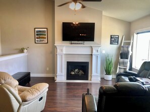 A living room with a fireplace, a mounted TV, and a ceiling fan. - Centrally located, clean and comfy (Heber City)