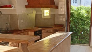Een keuken met een houten eiland, een inbouwoven en uitzicht op groen.