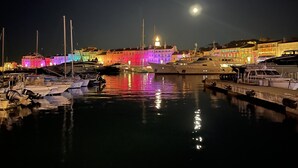 Una marina di notte, con imbarcazioni ormeggiate e edifici illuminati sullo sfondo.