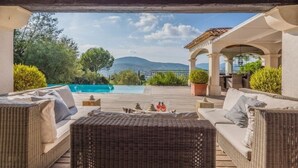 Un'area relax all'aperto con mobili in vimini, una piscina e vista sulle montagne.