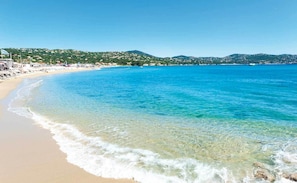 Una spiaggia con acque cristalline, una battigia sabbiosa e un paesaggio collinare sullo sfondo.