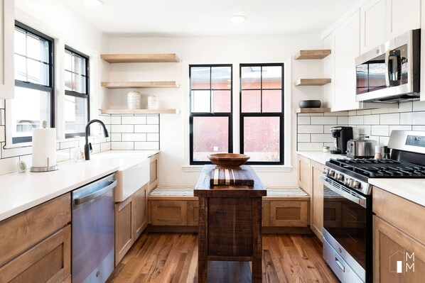 A modern kitchen with wooden cabinets, a built-in oven, and a large window with a view of the city.