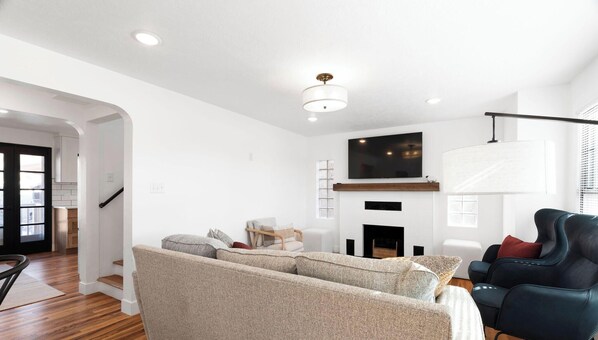A modern living room with a sofa, a black armchair, and a fireplace.