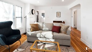 A modern living room with a grey sofa, black armchair, and a wooden coffee table.