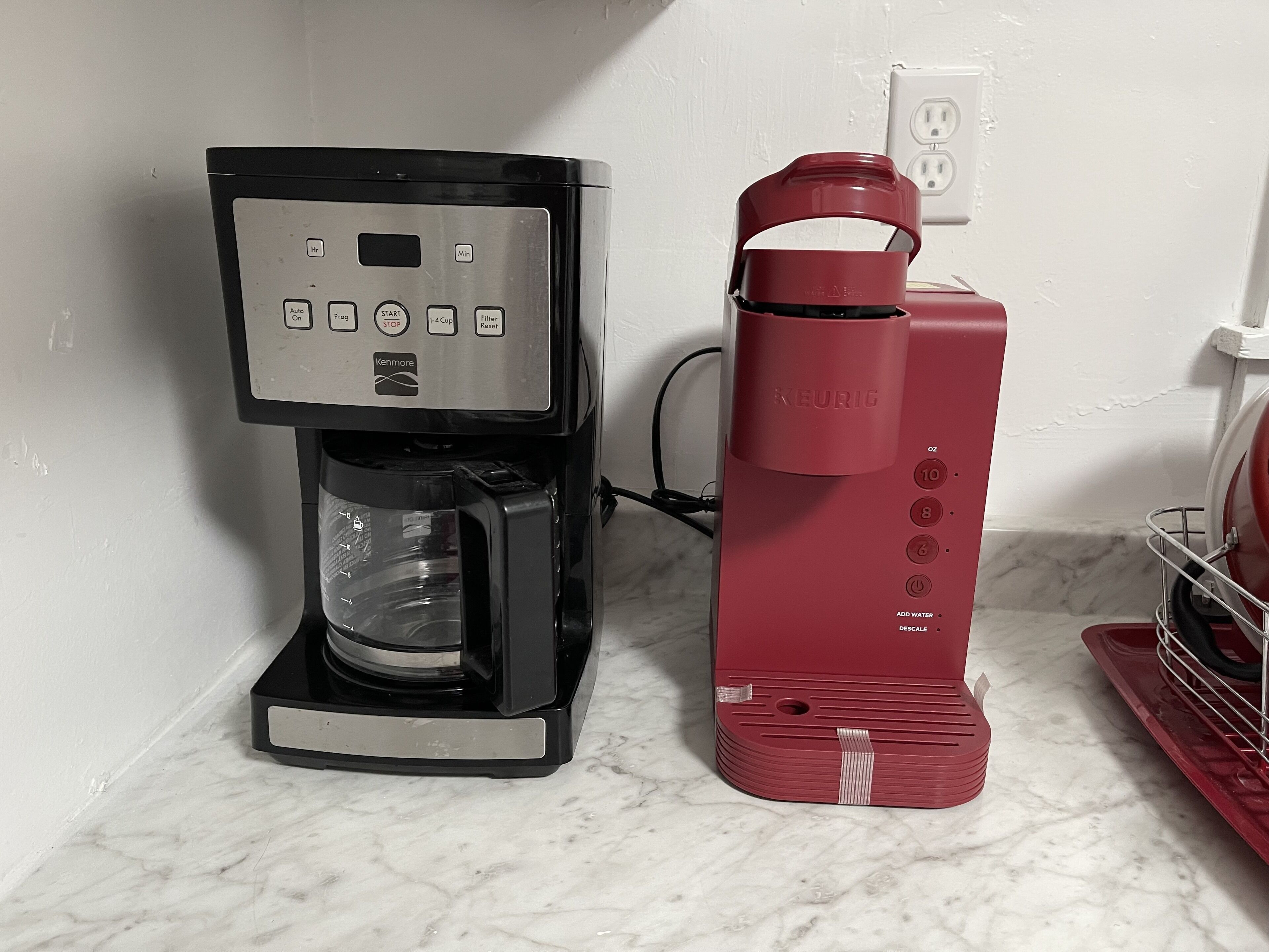 Une machine à café et un distributeur d’eau rouge sont posés sur le plan de travail de la cuisine.