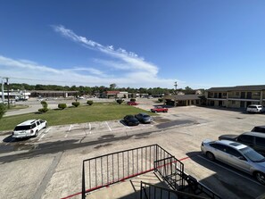 Um estacionamento com vários carros, um edifício com telhado plano e céu claro.