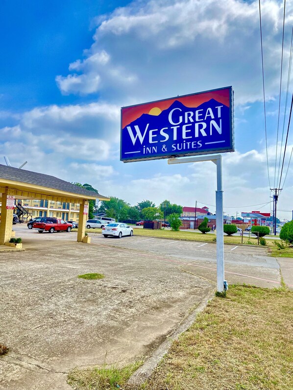 Placa do Great Western Inn & Suites, com boa visibilidade do estacionamento e um edifício ao fundo.