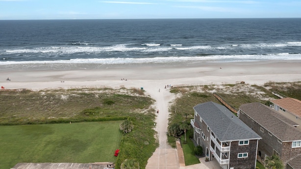 Ein Luftbild eines Strandes mit einem Weg, der zu einem Gebäude mit einem Balkon führt.