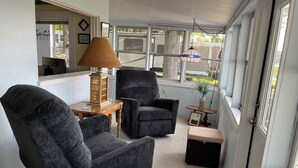 A cozy room with a large window, a lamp, and two armchairs.